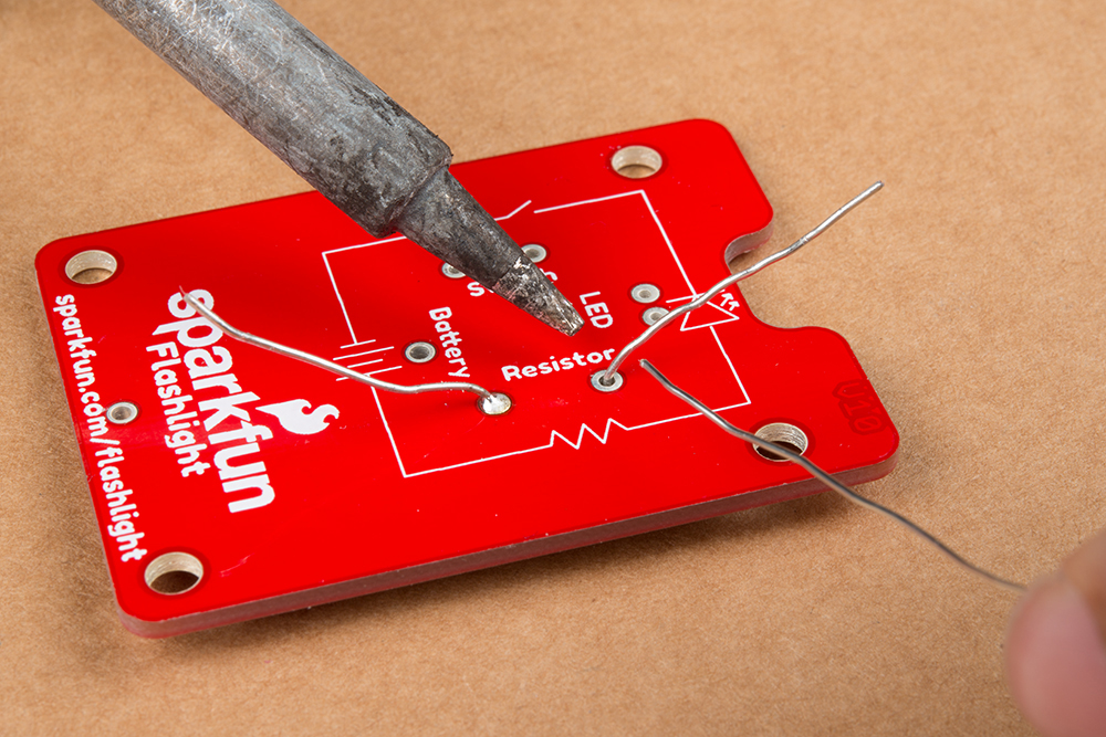 Photo of resistor being soldered to the board