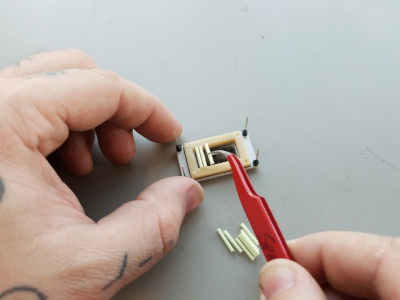 Tweezers being used to place Tritium gas tubes into grooves in the rubber gasket.