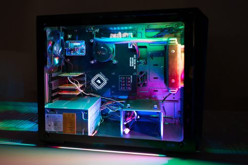 Photograph of an RGB lit side-window PC tower case housing a liquid cooler and a number of expansion cards