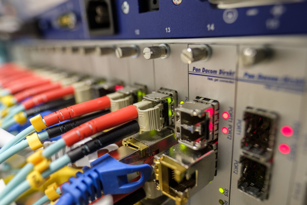 Stock image of fiber optic cables plugged into a piece of network equipment