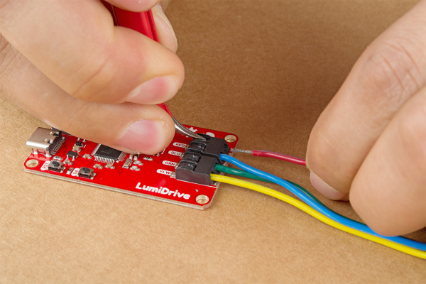 Inserting the wire into the poke home clamp with the black flap pressed down by tweezers